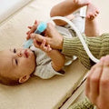 Baby using nasal aspirator for gentle mucus removal, safe infant care tool